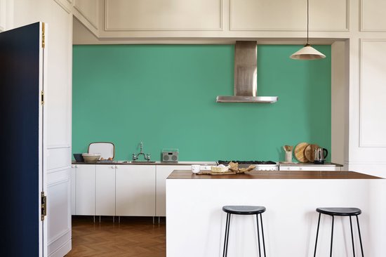 Keuken met witte kasten, een houten aanrecht en een groene muur.