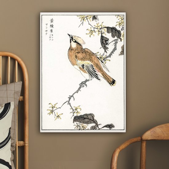 Une estampe japonaise d'un oiseau sur une branche fleurie, accrochée à un mur brun à côté d'une chaise en bois.
