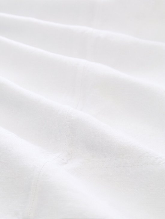 Gedetailleerde textuur van witte linnen stof met subtiele plooien.