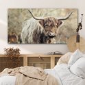 Interieur slaapkamer met een glasschilderij van een Schotse Hooglander boven een houten dressoir.