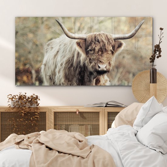 Interieur slaapkamer met een glasschilderij van een Schotse Hooglander boven een houten dressoir.