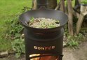 Zwarte BonFeu tuinhaard met wok, met wokschotel met groenten erop.