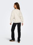 Model draagt een lichtgrijze sweater met lange mouwen van achteren, gecombineerd met een zwarte jeans.