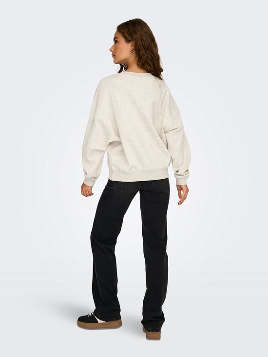 Model draagt een lichtgrijze sweater met lange mouwen van achteren, gecombineerd met een zwarte jeans.