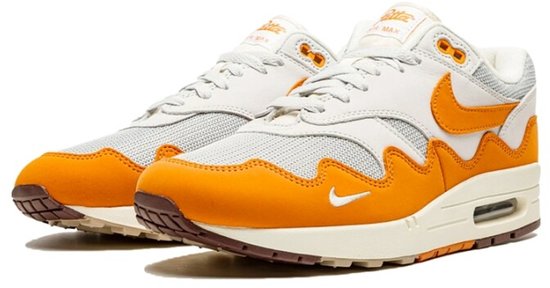 Witte en oranje Nike Air Max 1 Patta sneakers met beige zolen en bruine details, op een witte achtergrond.