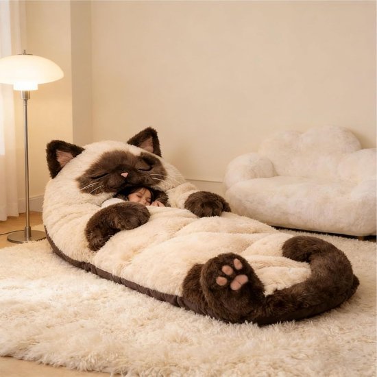 Kind slaapt in een grote, lichte en bruine kattenvormige slaapzak op een vloerkleed.