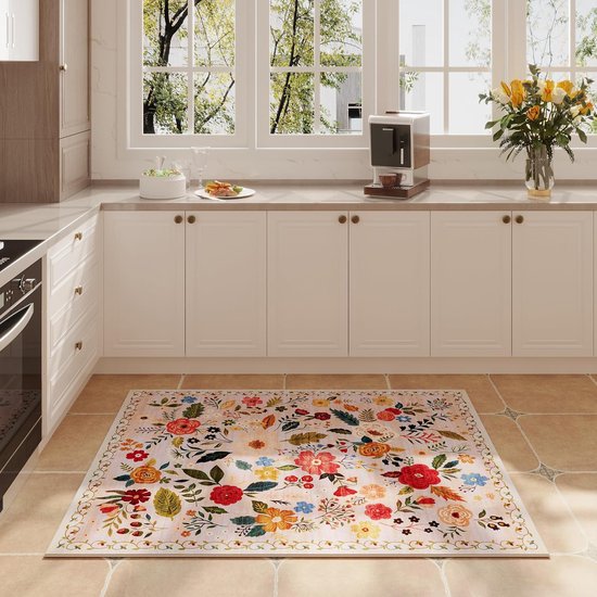 Een langwerpig, lichtroze kleed met een bont bloemenpatroon dat de vloer van een moderne keuken siert.