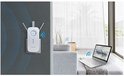 TP-Link WiFi Range Extender in een stopcontact, naast een laptop in een woonkamer.