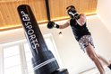 Man met bokshandschoenen slaat tegen zwarte AJ-Sports bokspaal.