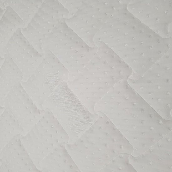 Detail van de witte topper met ruitvormige stiksels en kleine stippen.