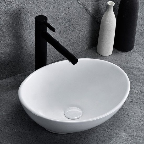 Lavabo blanc ovale à poser avec robinet noir sur fond de carrelage gris.