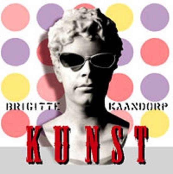 Buste van Brigitte Kaandorp met zonnebril voor een achtergrond met gekleurde stippen, tekst 'Brigitte Kaandorp Kunst'.