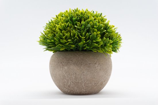 Plante artificielle verte aux feuilles semblables à de l'herbe dans un pot rond gris.