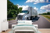 Behang - Fotobehang Wit gekleurde vrachtwagen op een snelweg - Breedte 600 cm x hoogte 400 cm