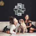 Witte fotolijst met 9 vakjes voor foto's en tekstvakken, hangend aan een muur boven een bank waar twee meisjes met een puppy op zitten.