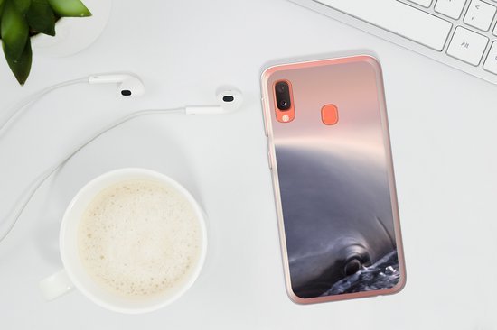 Transparante hoes met dolfijnprint op een telefoon, naast koffie en oortjes.