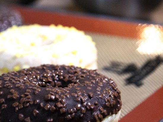 Chocolade donut met hagelslag op een beige bakmat met bruine rand.
