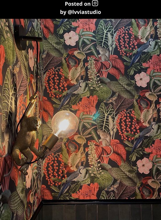 Gouden wandlamp met aap en gloeilamp, aan een muur met jungle-behang.