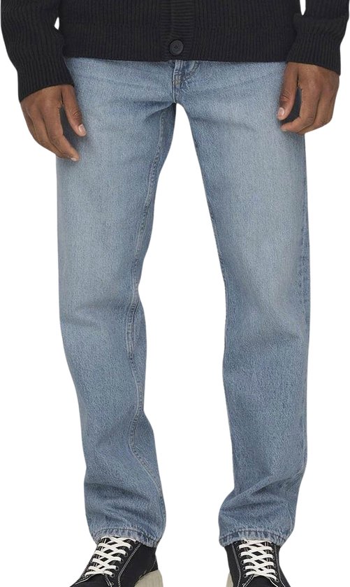 Man in een lichtblauwe jeans met een zwart gebreid vest.