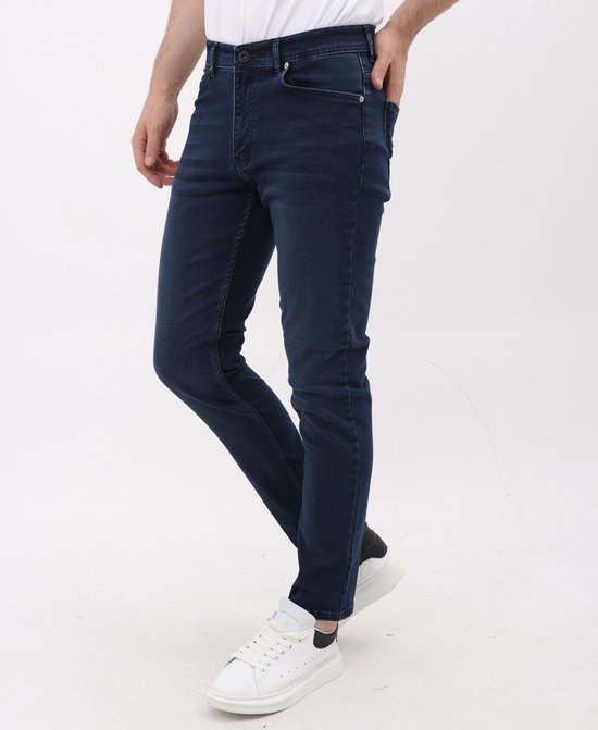Blauwe stretch jeans met regular fit voor heren. Gedragen met witte sneakers.