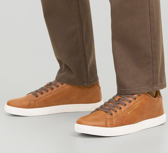 Model draagt bruine leren Jack & Jones sneakers met witte zolen en bruine broek.