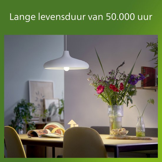 Een eettafel met een moderne witte hanglamp en een vaas met bloemen.