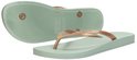 Een lichtgroene Ipanema slipper met koperkleurige band, naast de zool van een identieke slipper.