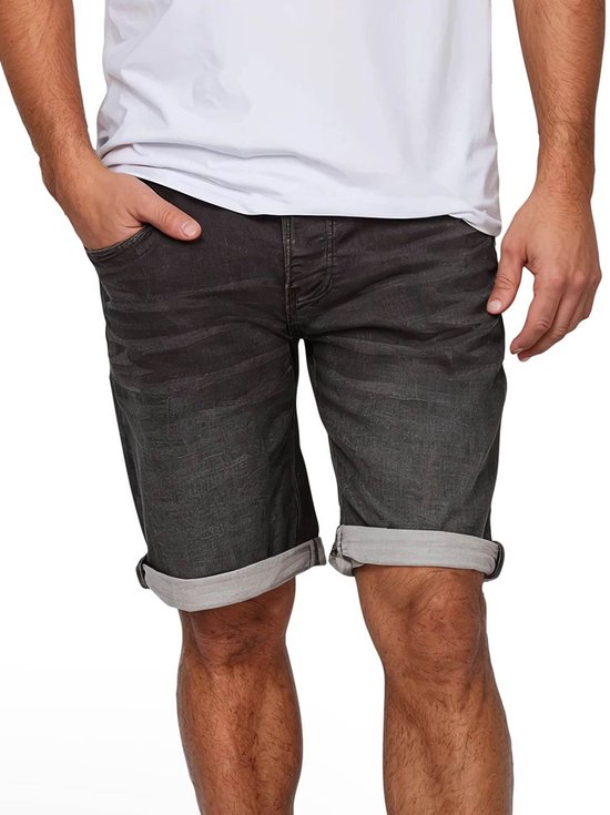 Man met grijze denim short met omgeslagen broekspijpen en witte t-shirt.