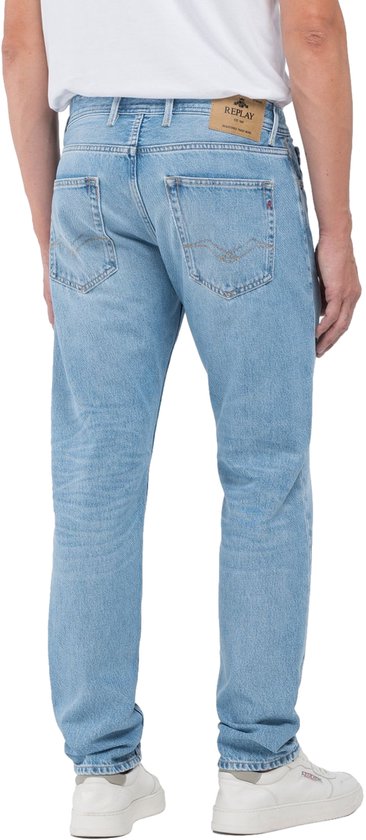 Homme en jean Replay bleu clair, le dos est visible. Le pantalon a une étiquette Replay en cuir au dos.