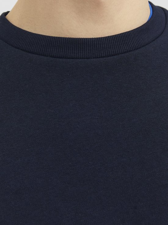 Detail van de geribbelde ronde hals van een donkerblauwe sweater met een blauwe rand zichtbaar.