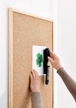 Handen gebruiken een zwarte nietmachine op een prikbord met klaverblad.