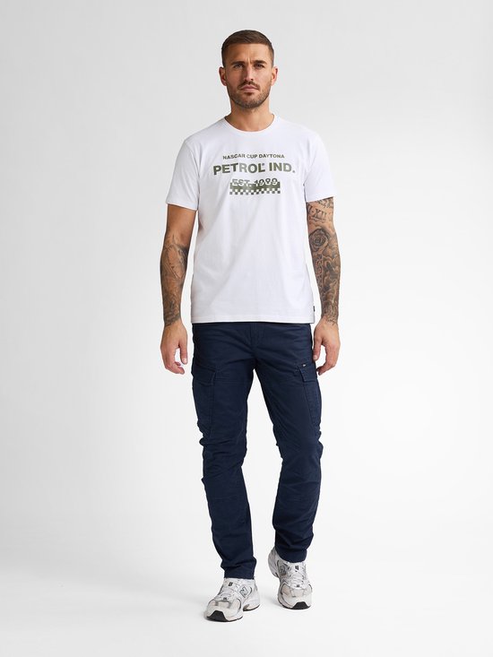 Man in volledig donkerblauwe cargobroek en witte t-shirt met tekst.