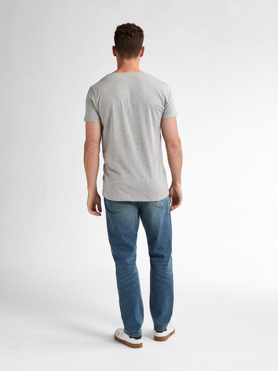 Man van achteren gezien, draagt een grijze basic T-shirt met korte mouwen en blauwe jeans.