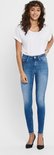 Model draagt een skinny jeans met een blauwe denim wassing en rafelige zoom, gecombineerd met zwarte pumps.