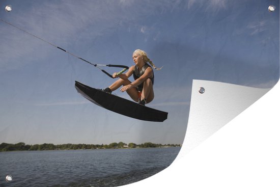 Foto: Tuindecoratie een sportieve vrouw gaat laag door haar knie n op een wakeboard 60x40 cm tuinposter tuindoek buitenposter