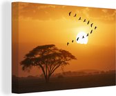Canvas Schilderij Zwerm nijlgans vogels vliegen in een V-formatie tijdens de zonsondergang in Kenia - 90x60 cm - Wanddecoratie