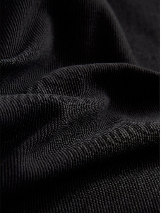Gedetailleerde textuur van zwarte jersey denim stof, met plooien.