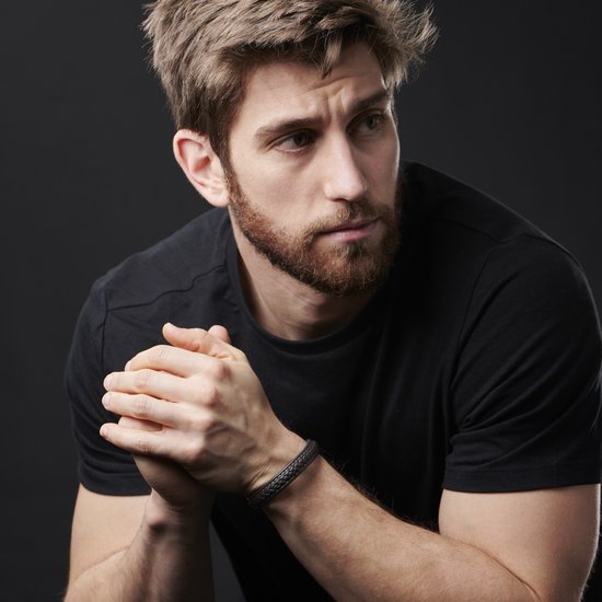 Man met baard draagt een zwarte t-shirt en een donker gevlochten leren armband.