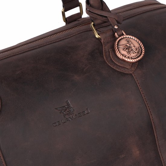 Detail van een donkerbruine leren weekendtas met merklogo en decoratieve hanger.