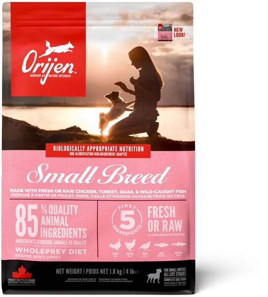 Roze zak Orijen Small Breed hondenvoer met op de voorgrond een silhouet van een vrouw en een hond bij zonsondergang.