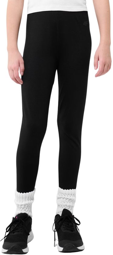 Gros plan sur le bas du corps d'une fille portant un legging noir avec logo 4F, des chaussettes blanches et des baskets noires.
