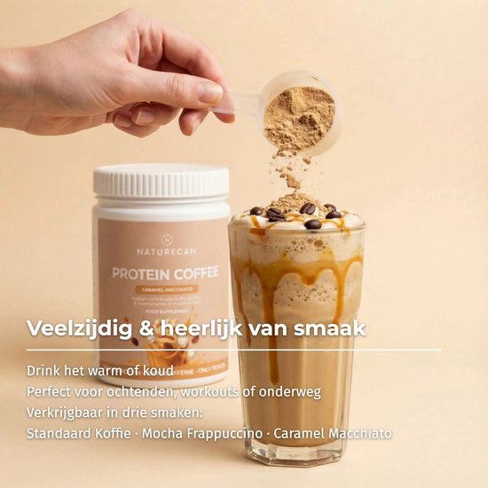 Een hand voegt bruin eiwitpoeder toe aan een glas met karamel macchiato proteïne koffie, gegarneerd met slagroom en koffiebonen.