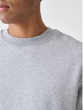 Close-up van een grijze sweater met ronde hals in ribbelstructuur, gedragen door een man.