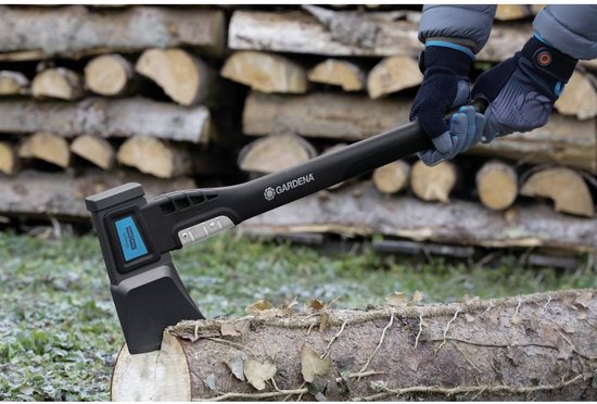 GARDENA bijl in een boomstronk, vastgehouden door handen met grijze en blauwe handschoenen.