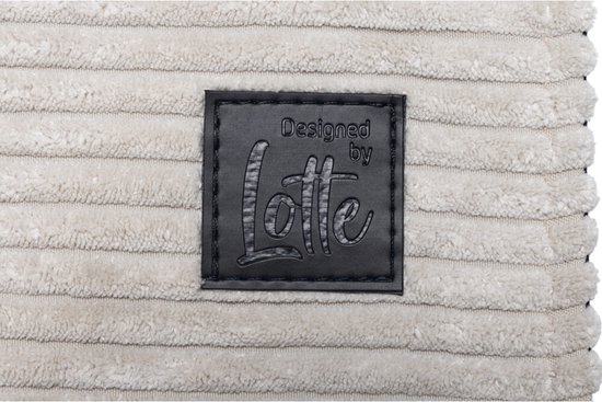 Close-up van een zwart logo met 'Designed by Lotte' op een lichtgrijs, geribd hondenkussen.