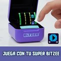 Paars Bitzee-doosje met open deksel. Het scherm toont een spel met groene en paarse lichten. Een vinger raakt het scherm aan. "JUGA CON TU SUPER BITZEE" tekst.