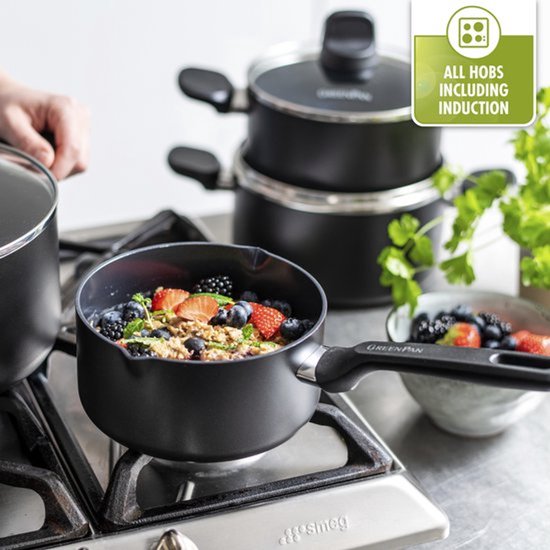 Une casserole de flocons d'avoine et de baies est sur une cuisinière à gaz. Une autre casserole est empilée à l'arrière.