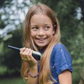 Meisje met lang blond haar, die een groene Kidywolf KIDYTALK walkietalkie vasthoudt.
