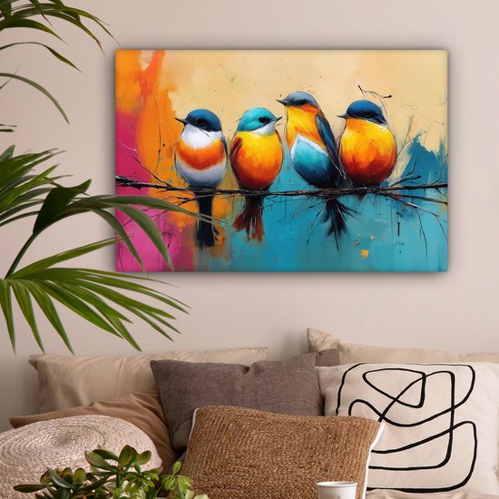 Vier kleurrijke vogels op een tak, hangend aan een muur boven een bed. De achtergrond is een abstracte mix van oranje, roze, blauw en geel. Een plant is zichtbaar aan de linkerkant.