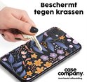 Hand toont een sleutel die de achterkant van een telefoonhoes met bloemenprint raakt.